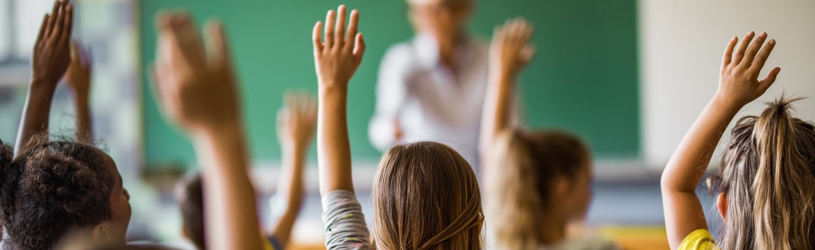 Children in a class room with their hands raised